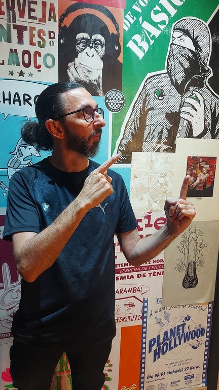 Eduardo F. S. Lima apontando para cartazes de exposição fotográfica